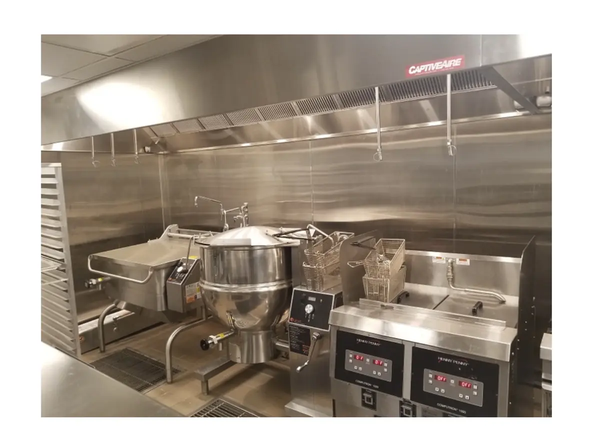 Commercial kitchen hood over a kettle and fryers